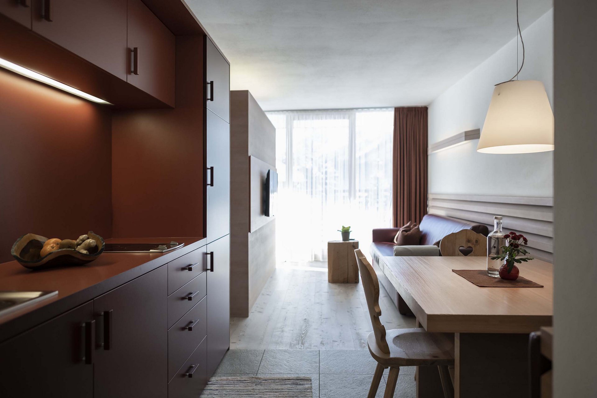 The Residence Königswarte Strata Modern living area with kitchenette, dining table and sofa in warm tones