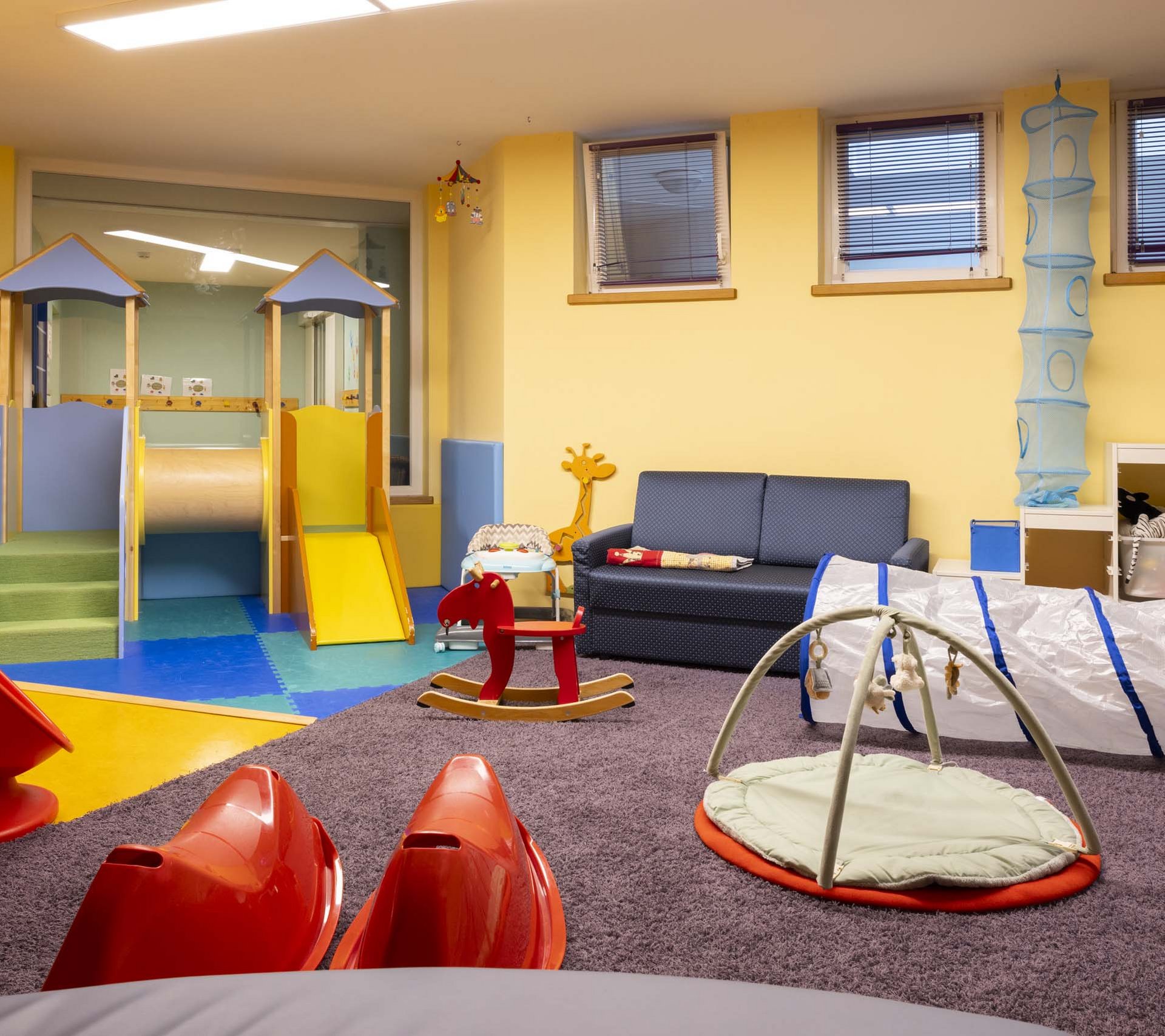 Property detail page - Hotel Rainer Children's playroom with slide, rocking horse, and sofa