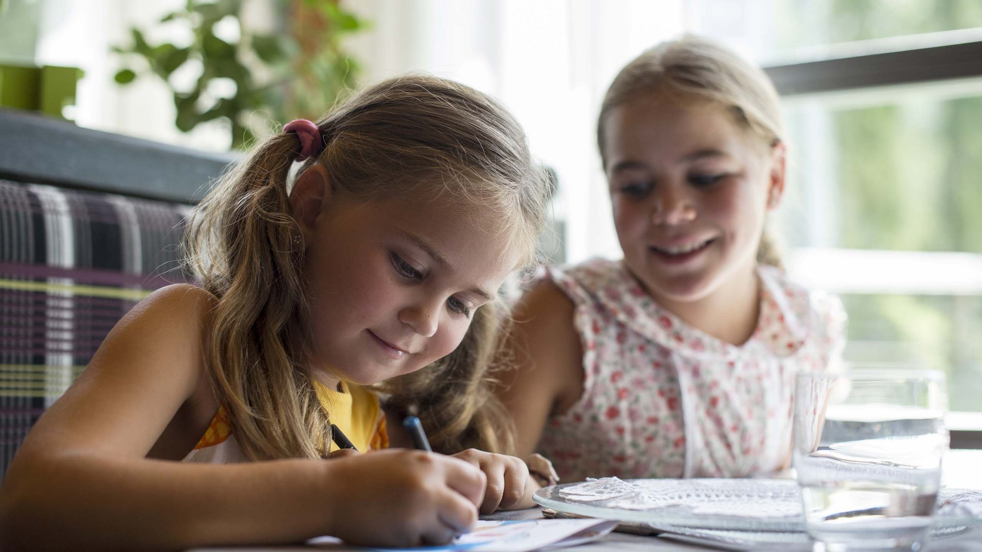 Family Resort Rainer Due ragazze sedute a tavola, una disegna concentrata