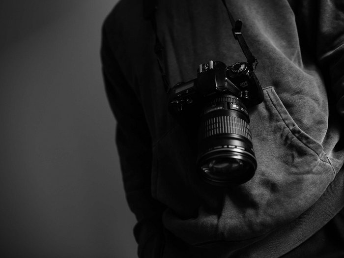 Let’s work together! Person wearing a DSLR camera with a long lens around the neck