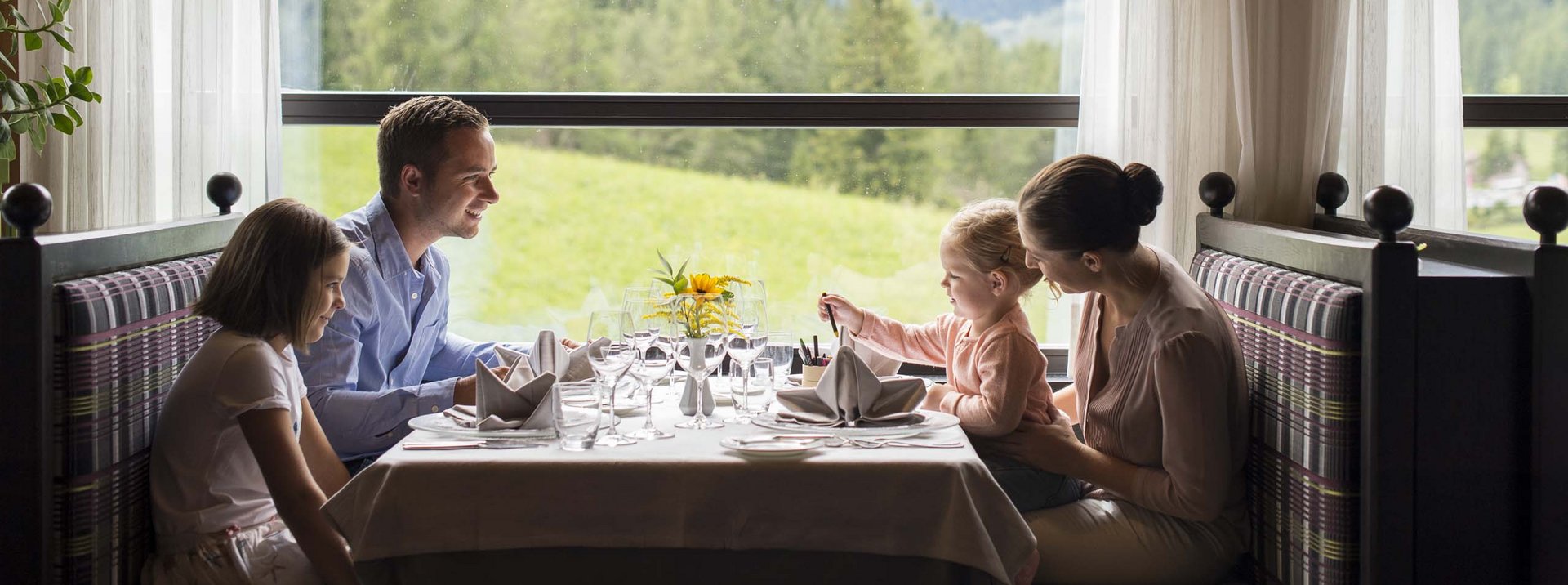 Stay at the Rainer: Family holidays in the Dolomites! Family having meal in restaurant with mountain view