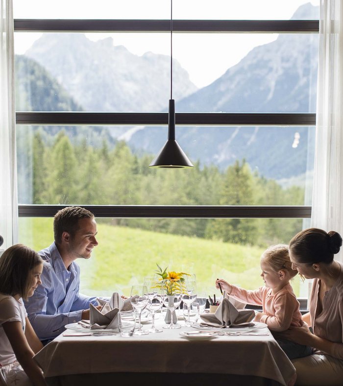 Family Resort Rainer: your accommodation in the Dolomites Family having meal in restaurant with mountain view