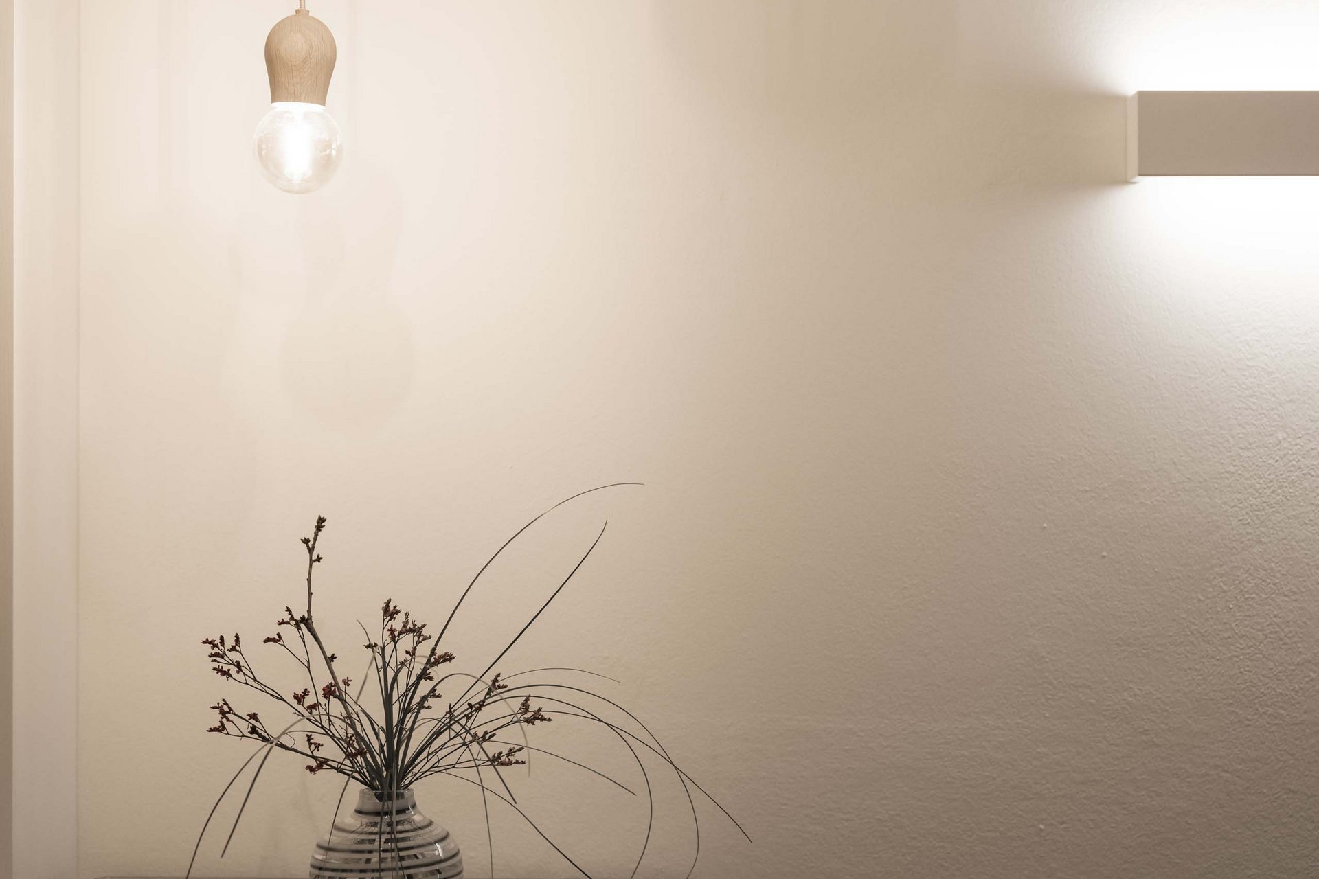 Naturerlebnis in der Villa Rainer Vase mit Pflanzen auf Glasplatte, beleuchtet von hängenden und Wandlampen