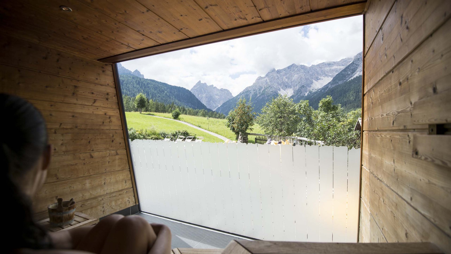 Family Resort Rainer Persona guarda fuori da una sauna verso montagne e paesaggio verde