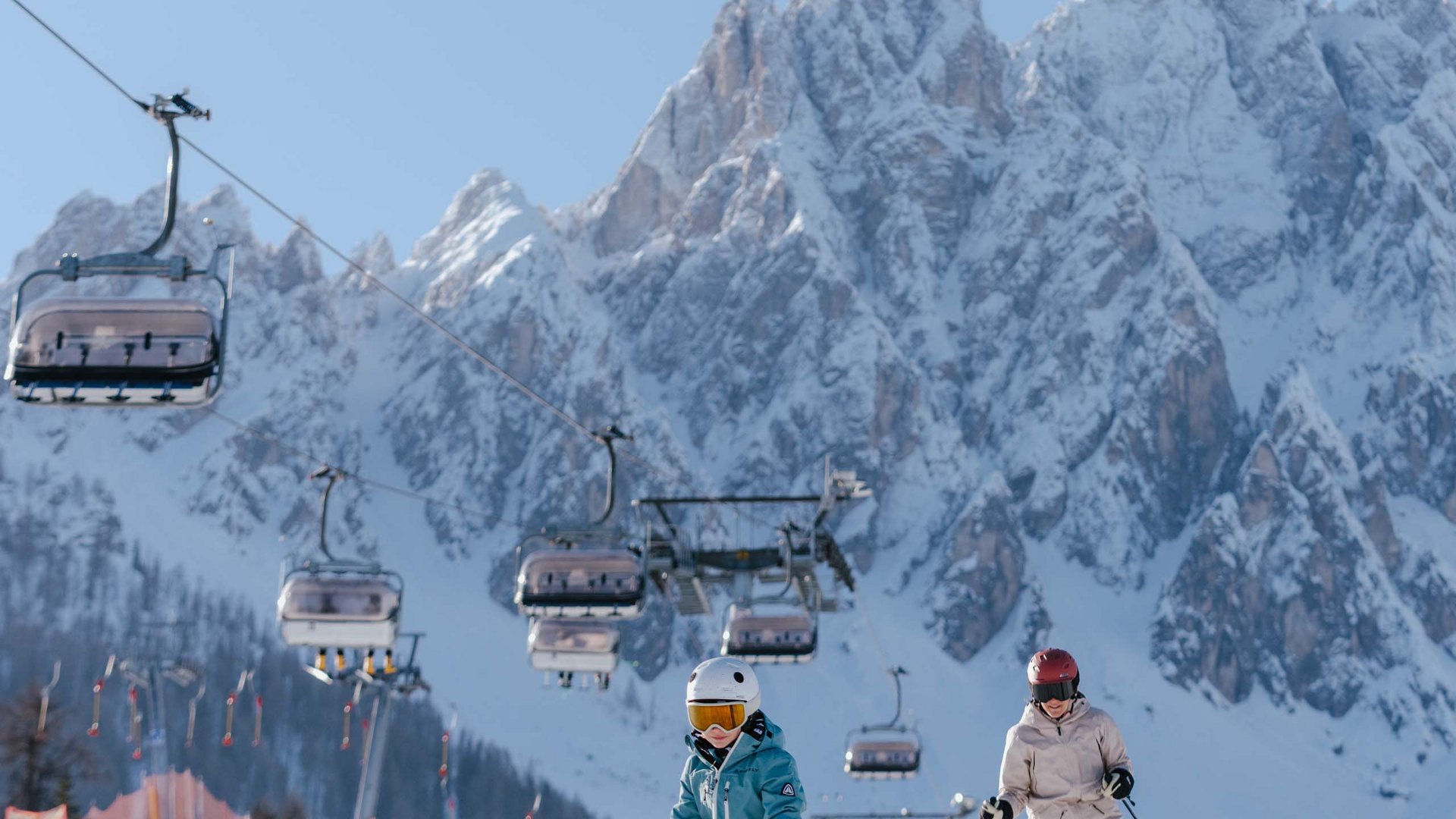 Qualche immagine del Rainer Due sciatori su una pista con seggiovie e montagne innevate sullo sfondo