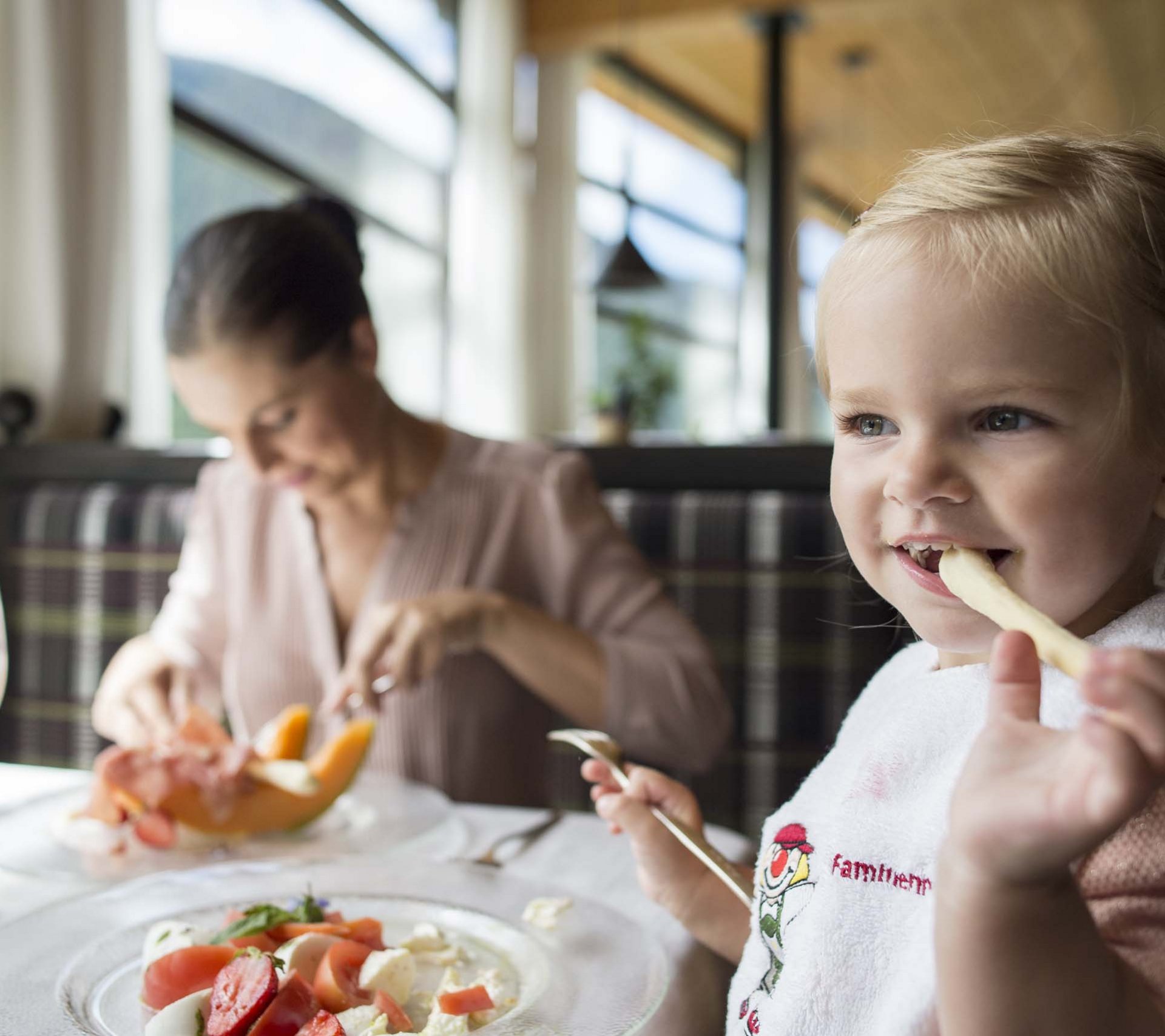 Property detail page - Hotel Rainer Little girl eating fries in a restaurant with a woman in the background