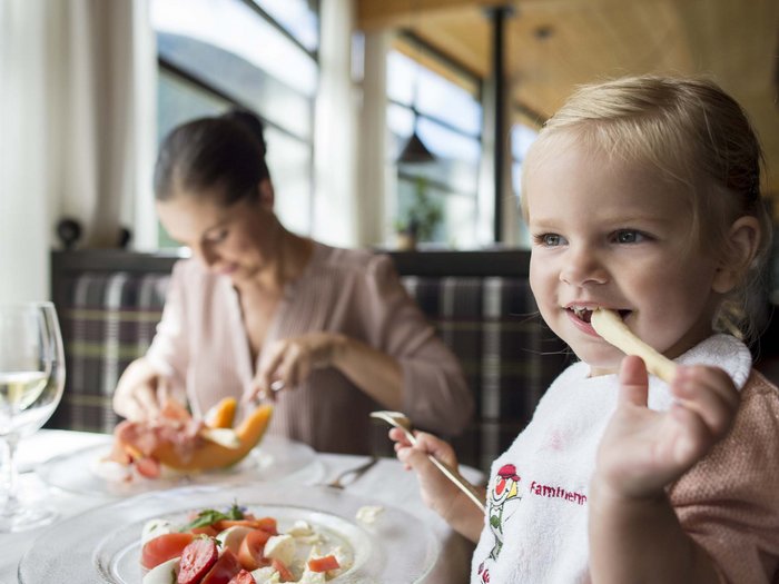 Gourmet delights from morning to night Little girl eating fries in a restaurant with a woman in the background