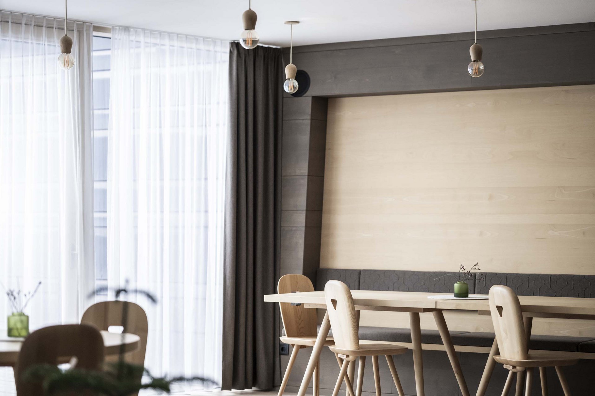 How to get to the Family Resort Rainer Modern dining room with wooden tables and chairs, large windows, and hanging lights