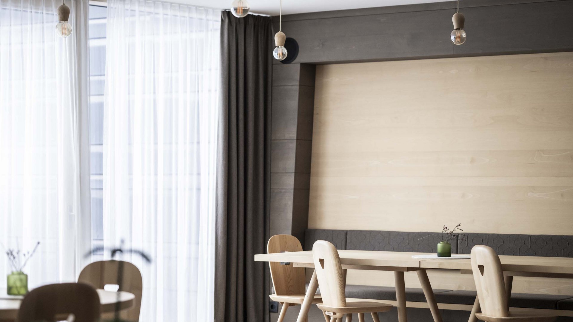 Residence Villa Rainer Sala da pranzo moderna con tavoli e sedie in legno, grandi finestre e lampade a sospensione