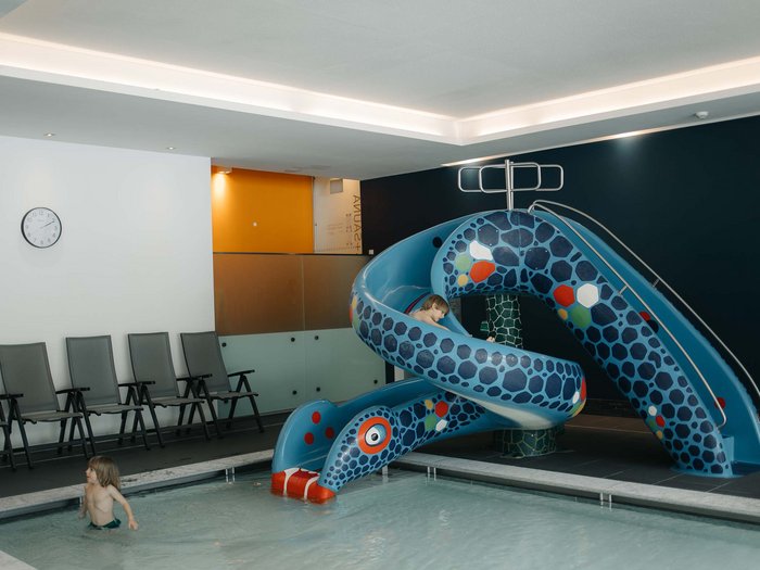 Children playing on a water slide in an indoor pool