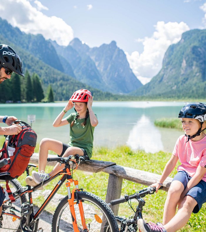 Family with bikes taking a break at alpine mountain lake on a sunny day