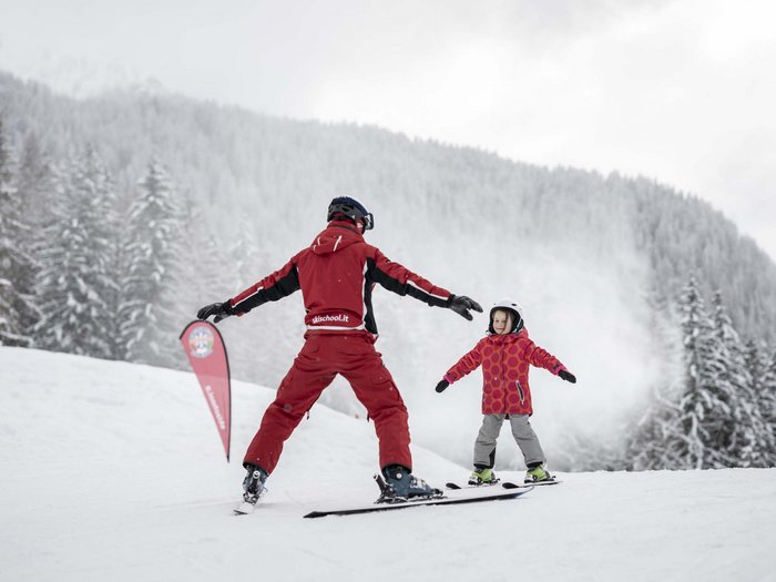 The in-house Rainer Ski School Ski instructor teaching child how to ski on snowy slope