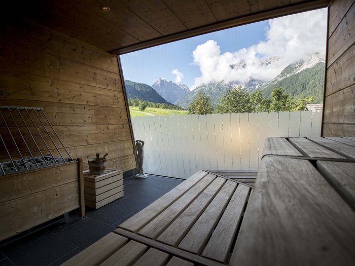 Relaxing wellness in the Dolomites: spa hotel in Sexten Wood sauna with benches and mountain view through large window