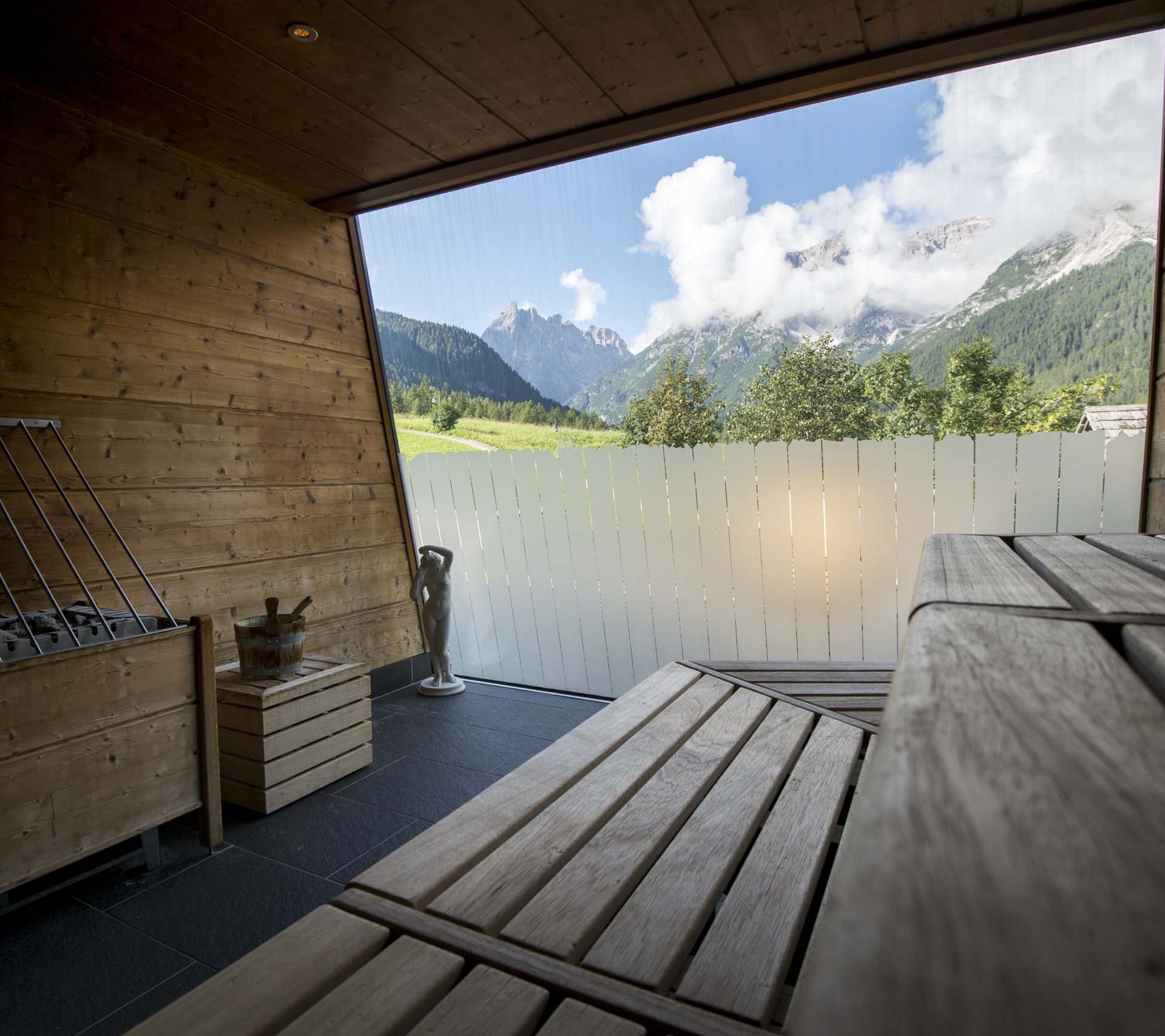 Property detail page - Hotel Rainer Wood sauna with benches and mountain view through large window