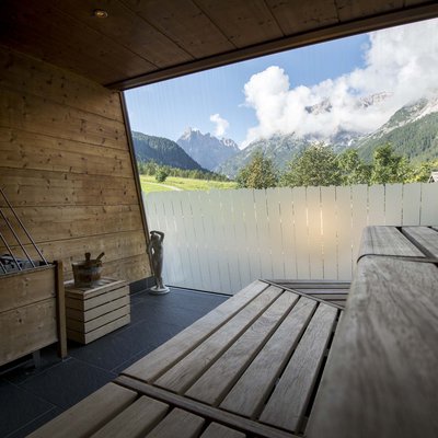 Ihr Familienresort in Südtirol Saunabereich mit Holzbänken und Bergblick durch großes Fenster