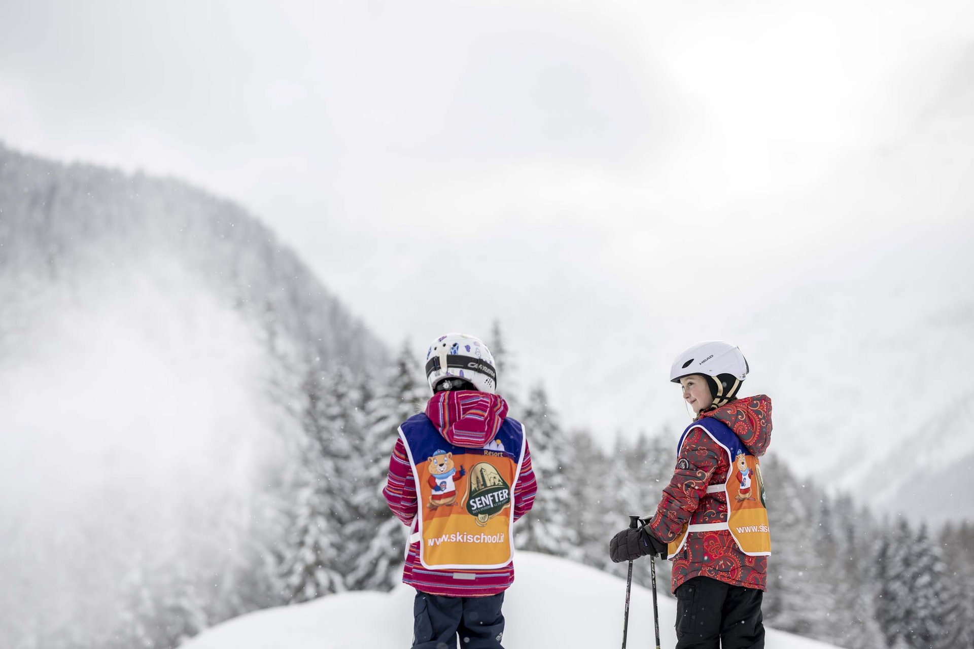 Ihr Familienresort in Südtirol Zwei Kinder mit Skiausrüstung und Warnwesten auf verschneiter Piste