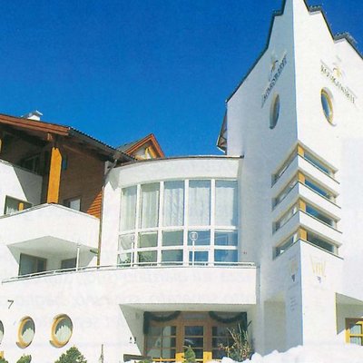 Edificio di hotel bianco con elementi in legno sotto un cielo blu chiaro