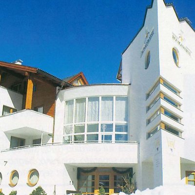 Edificio di hotel bianco con elementi in legno sotto un cielo blu chiaro