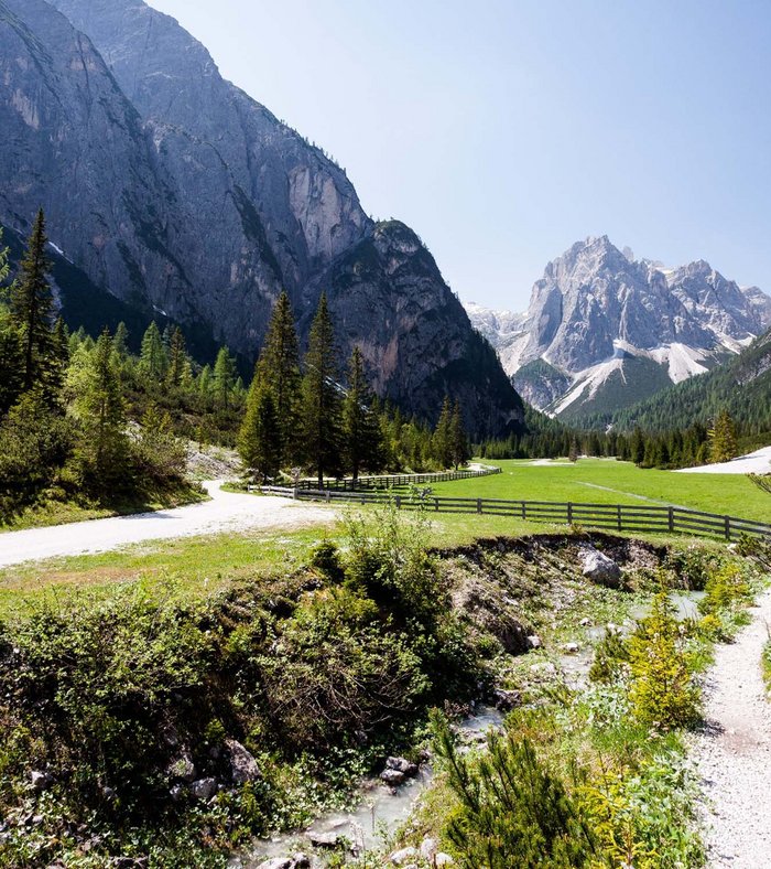 Sights around Sexten Trail through green alpine valley with tall mountain peaks
