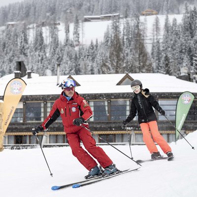 Puro divertimento al family hotel sulle piste da sci Istruttore di sci che insegna a una ragazza su una pista innevata con montagne sullo sfondo