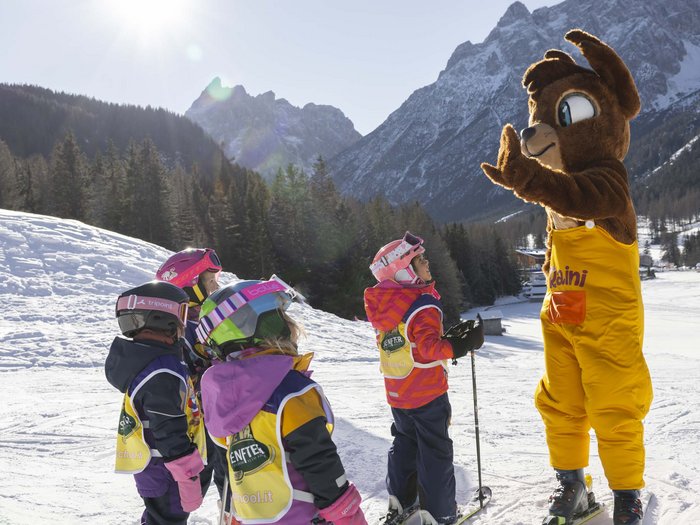 Bambini con attrezzatura da sci imparano con una maschera di orso sulla neve