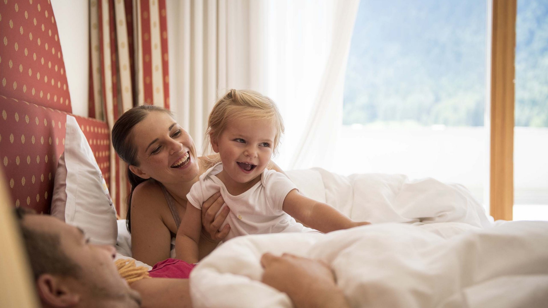 Family Resort Rainer Famiglia felice con bambino che gioca a letto in una camera luminosa
