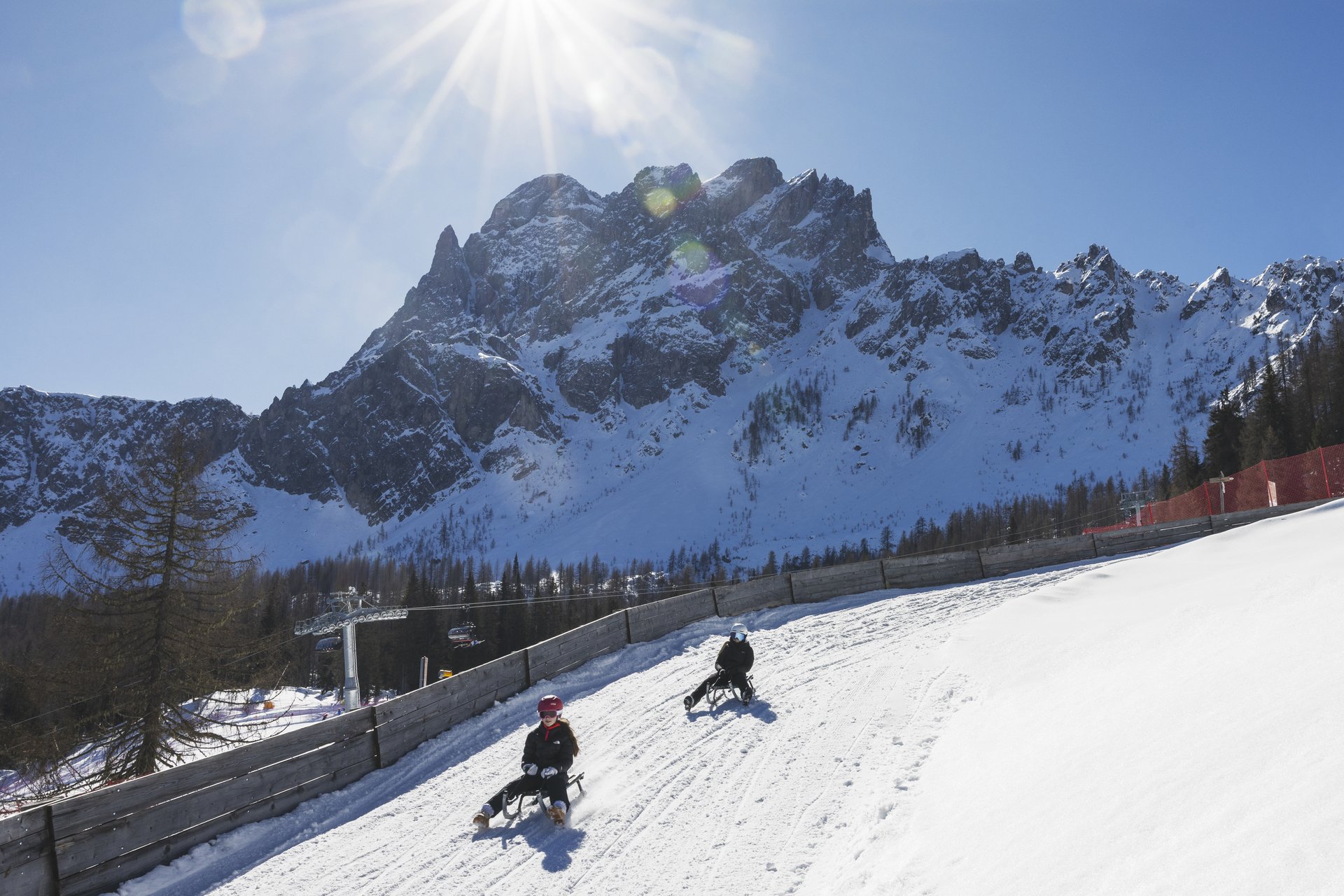 Il vostro family resort in Alto Adige Due slittinisti sulla pista da slittino. Sullo sfondo, la Rote Wand.