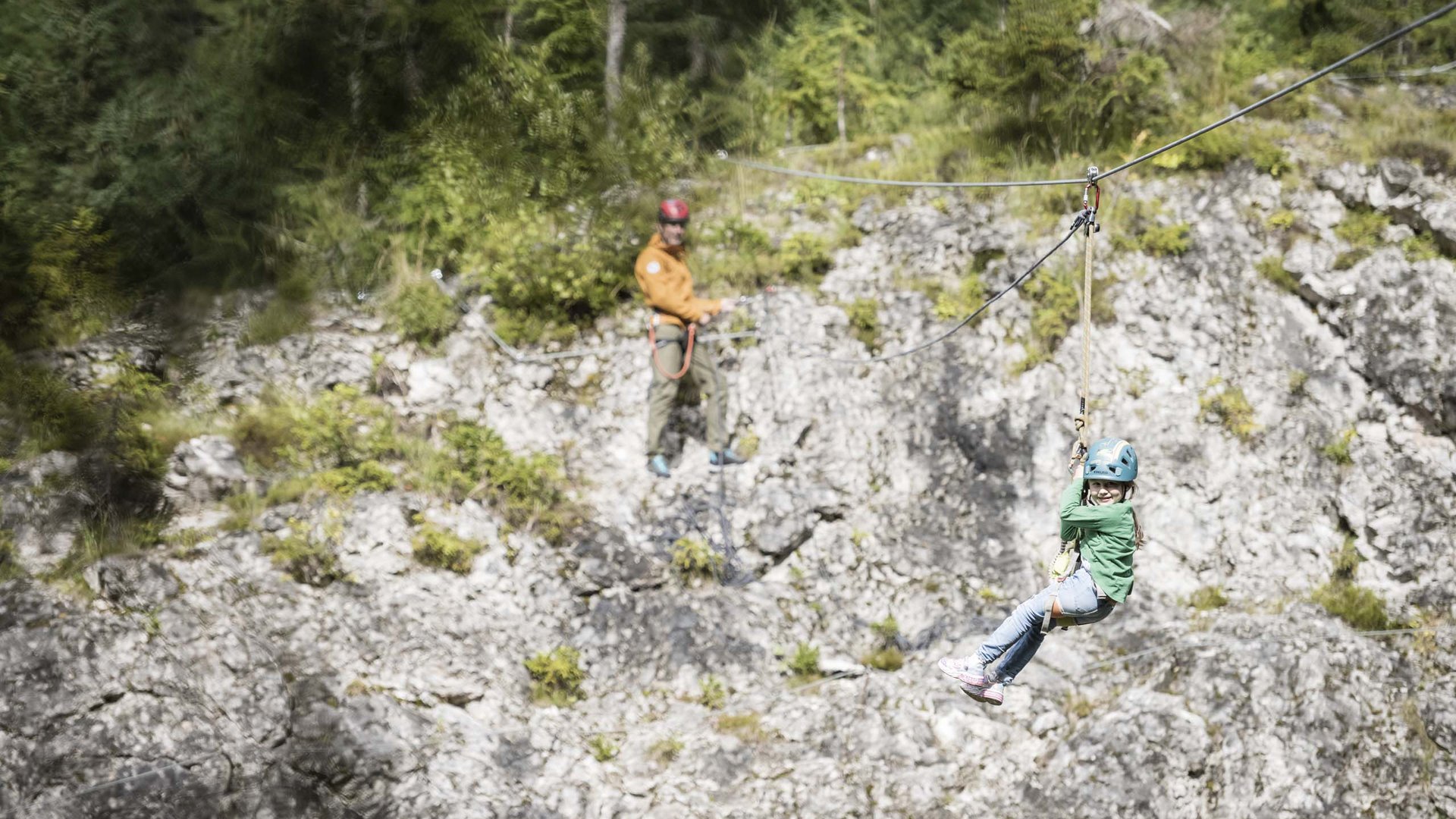 Qualche immagine del Rainer Bambino con casco su zipline sopra pendio roccioso e foresta