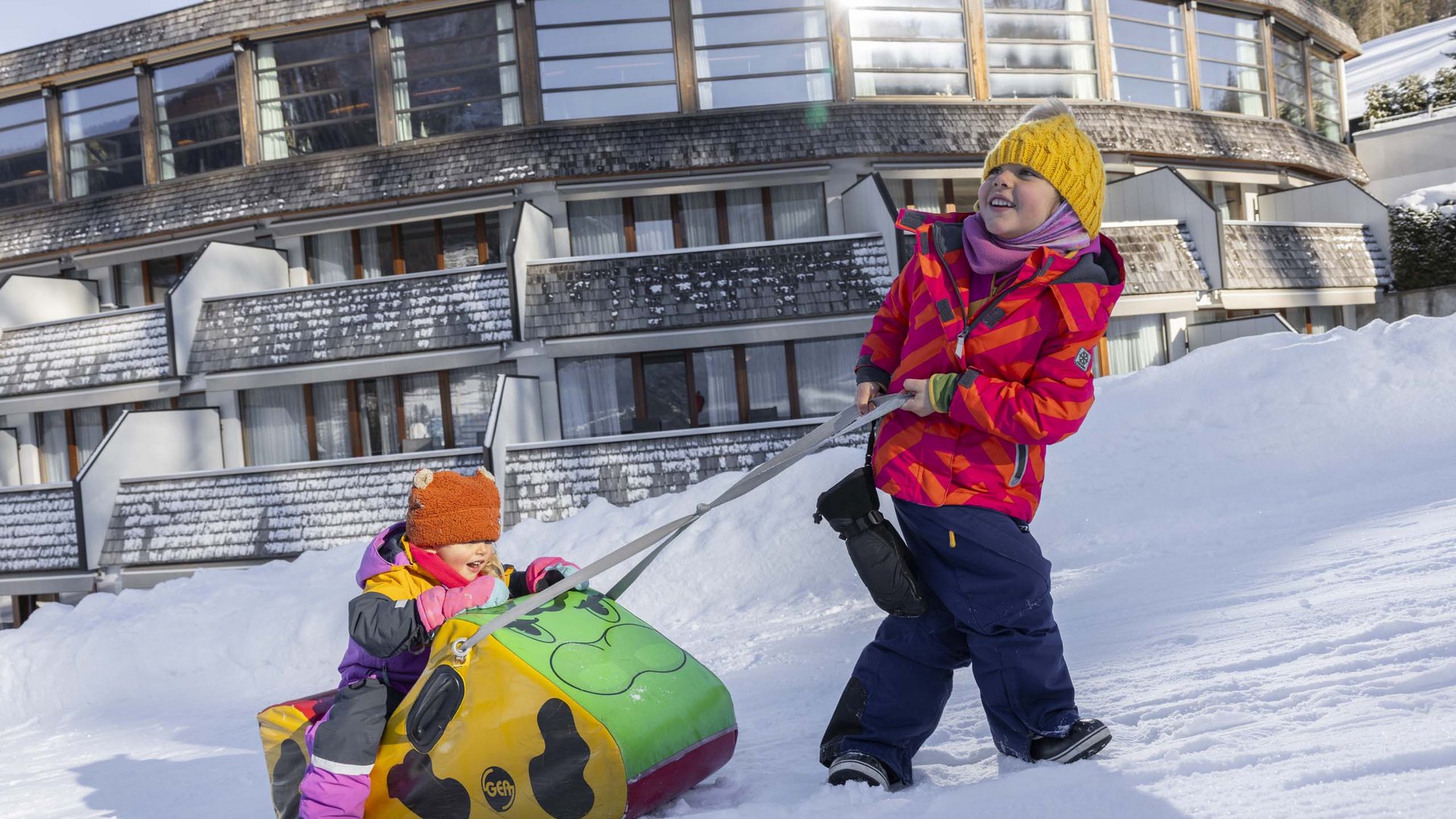Qualche immagine del Rainer Due bambini che giocano nella neve davanti a un grande edificio