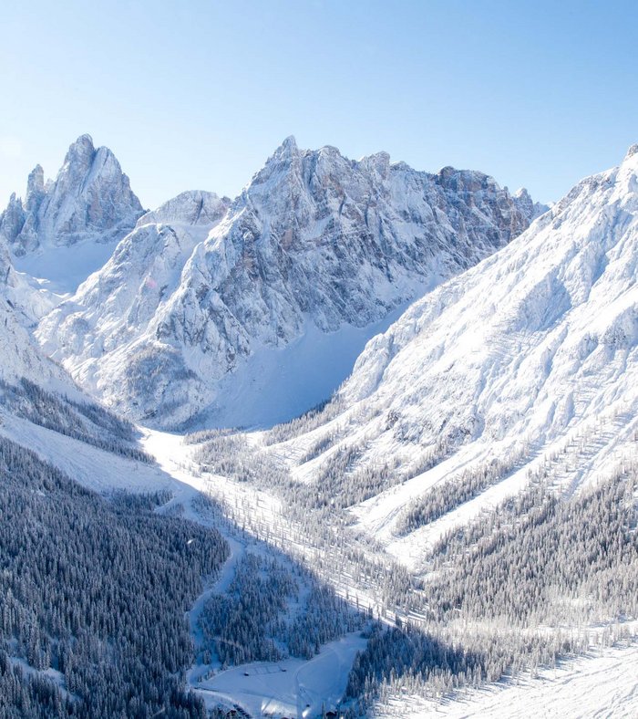 Sights around Sexten Snow-covered mountain landscape with pine forest under clear sky