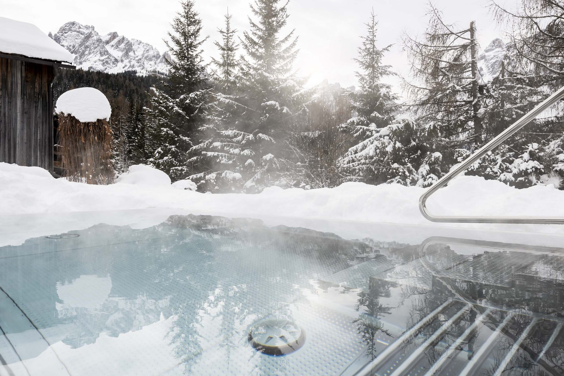 The Residence Königswarte Strata Steaming outdoor hot tub in snow with pine trees and snowy mountains