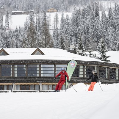 Schnee bedecktes Hotel in verschneitem Bergdorf mit Menschen im Freien