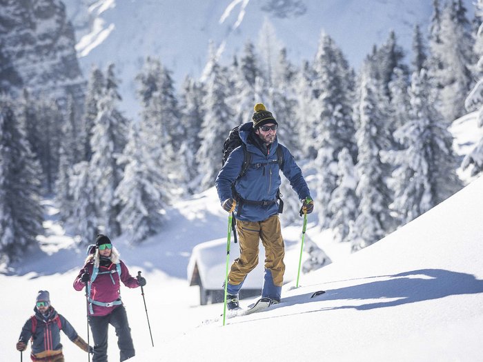 Winter sports away from the slopes Three people hiking on snow in sunny mountain landscape
