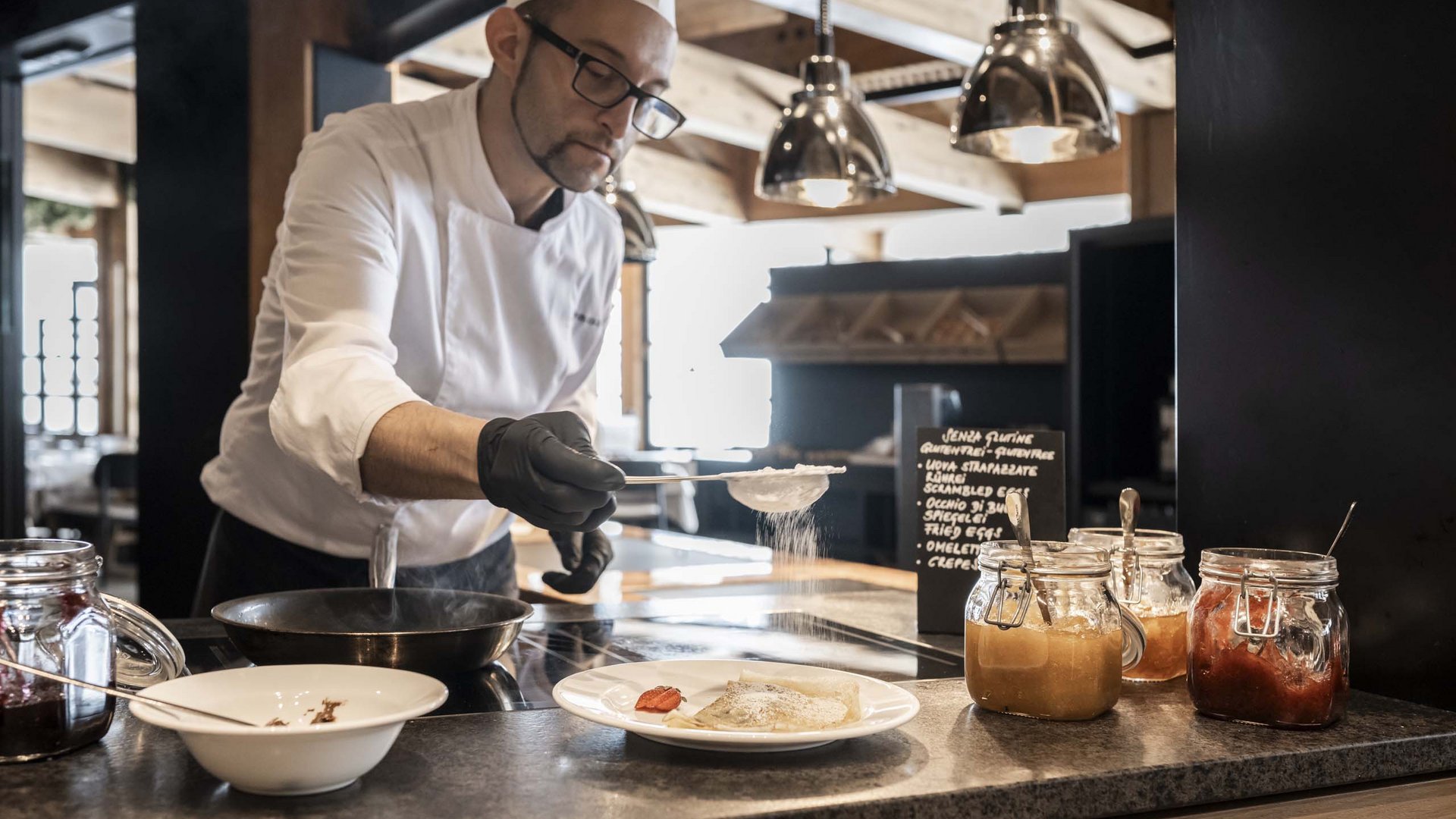 Family Resort Rainer Cuoco spolvera pancake con zucchero a velo in cucina moderna