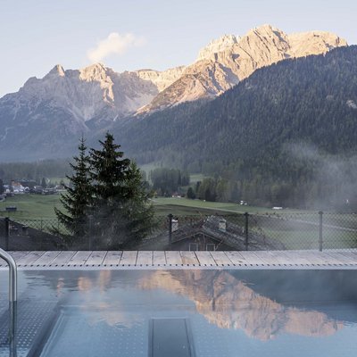 Relaxing wellness in the Dolomites: spa hotel in Sexten Steaming pool with Dolomites mountain view at sunrise