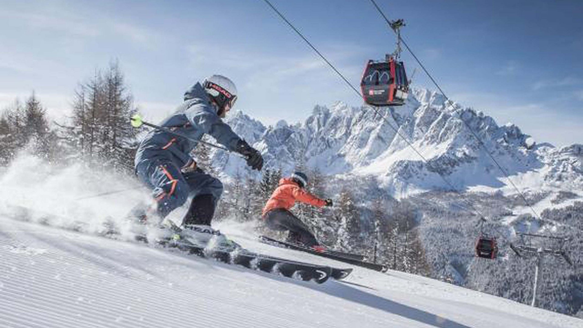Qualche immagine del Rainer Due sciatori su pista innevata con funivia e montagne sullo sfondo