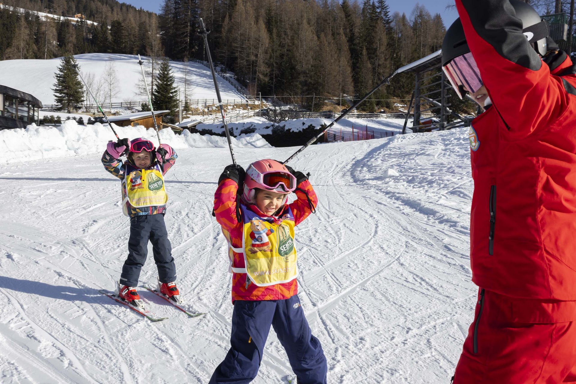 Ihr Familienresort in Südtirol Zwei Kinder beim Skifahren mit Skilehrer im Schnee