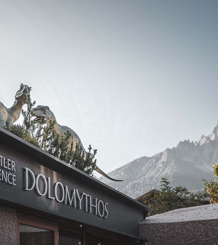 Sights around Sexten Wachtler Residence Dolomythos with dinosaur figures on the roof and mountain backdrop