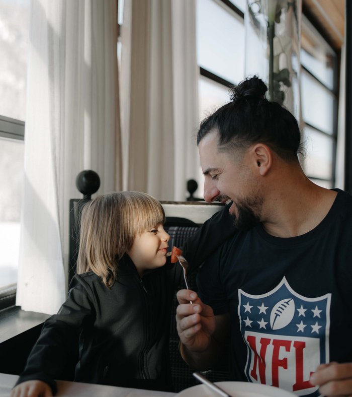 Padre che dà da mangiare ridendo al bambino a colazione