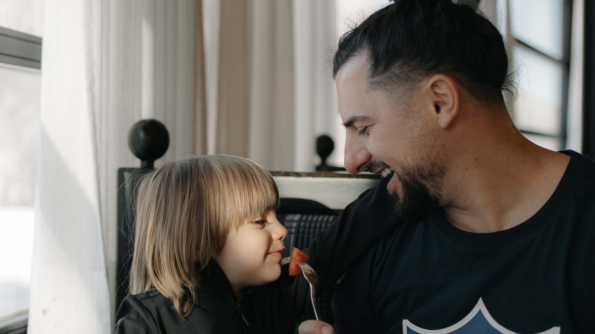 Family Resort Rainer Padre che dà da mangiare ridendo al bambino a colazione