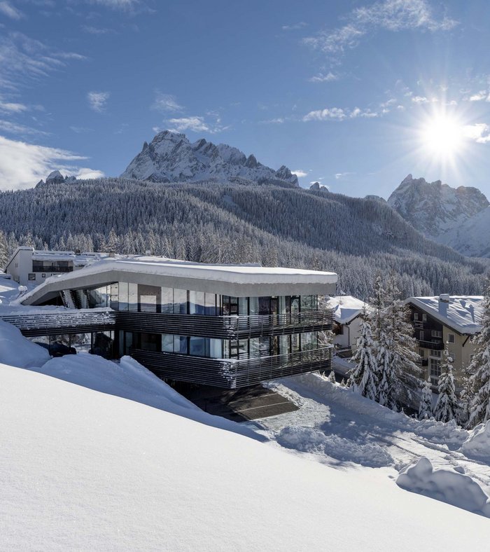 Modernes Hotel im Schnee vor verschneiten Bergen und klarem Himmel