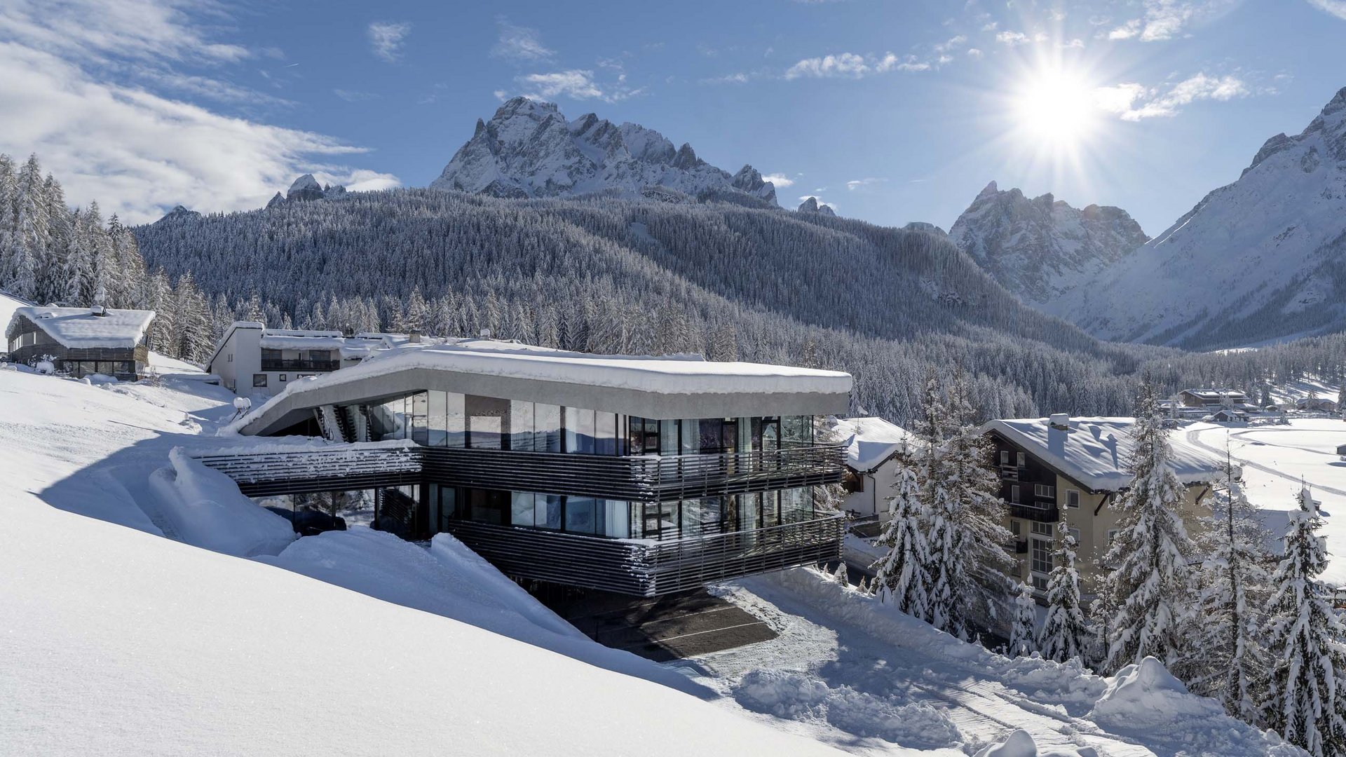 Residence Paramount Alma Hotel moderno nella neve con montagne innevate e cielo limpido