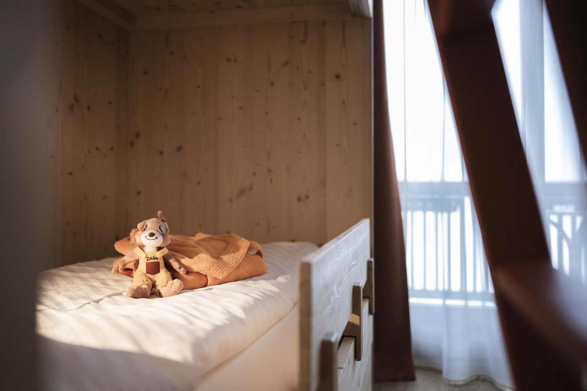 How to get to the Family Resort Rainer Stuffed animal on bed with orange towel in cozy wooden room