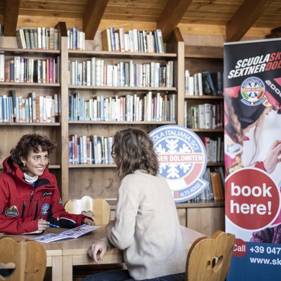 Puro divertimento al family hotel sulle piste da sci Due donne parlano in biblioteca della scuola di sci Sextner Dolomiti