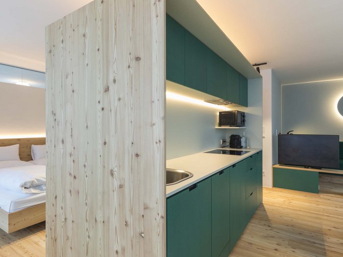 Modern studio with kitchenette, bedroom area, and seating space with TV