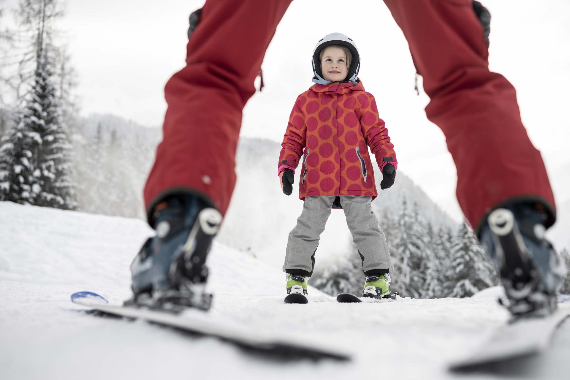 Bambino impara a sciare con istruttore su montagna innevata