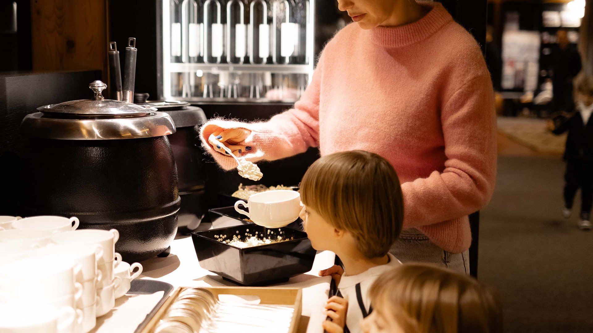 Family Resort Rainer Donna con due bambini che prende cibo da un buffet in un ristorante