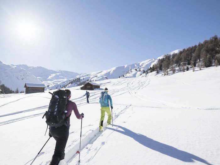Winter sports away from the slopes Three ski hikers trekking through snowy mountains on a sunny day