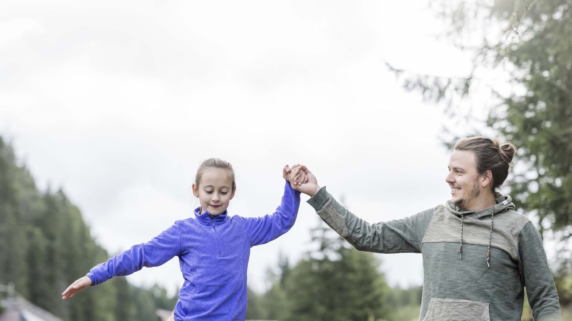 Qualche immagine del Rainer Padre aiuta la figlia ad equilibrare su una slackline all'aperto