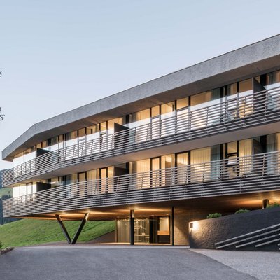 Edificio moderno con finestre illuminate in paesaggio collinare verde